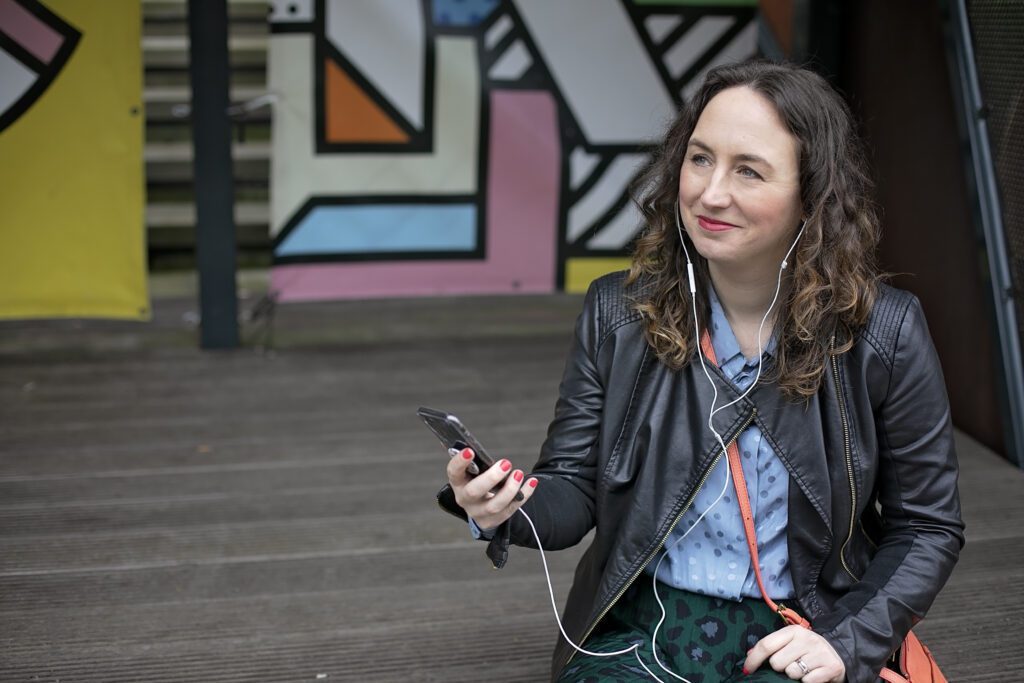 Female entrepreneur sat with a mobile phone and wearing earpods
