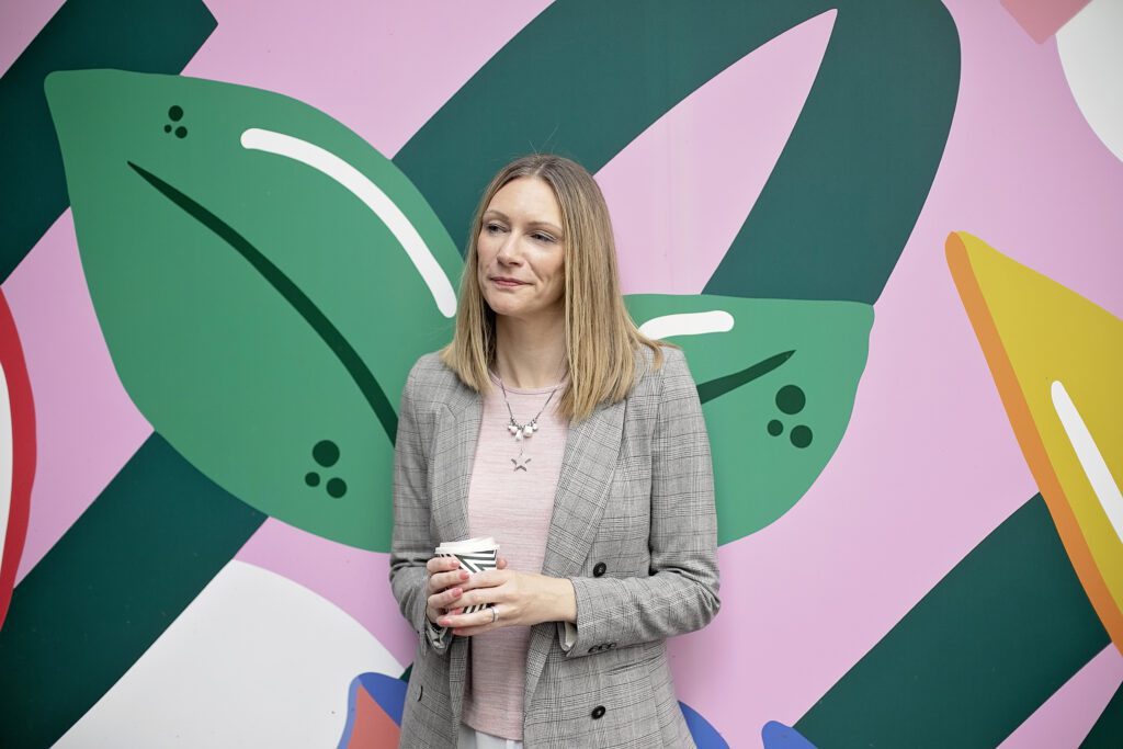 Entrepreneur holding a coffee cup against colourful wall