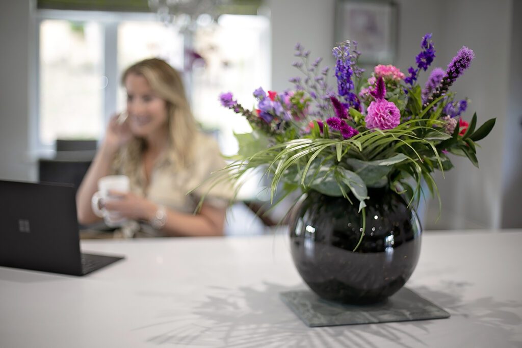 Flowers in a vase with business woman out of focus in background
